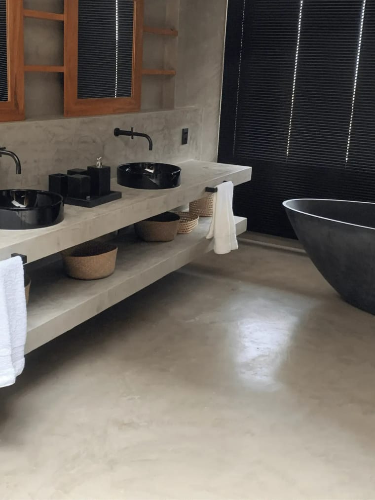 Banheiro com bancada, parede e piso em Cimento & Cor e uma banheira escura