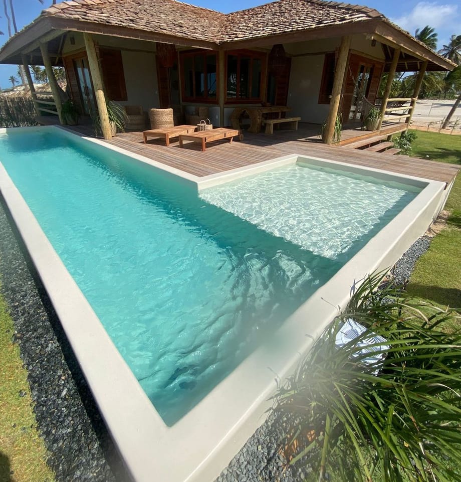 Casa de praia com piscina e deck de madeira, sob sol forte