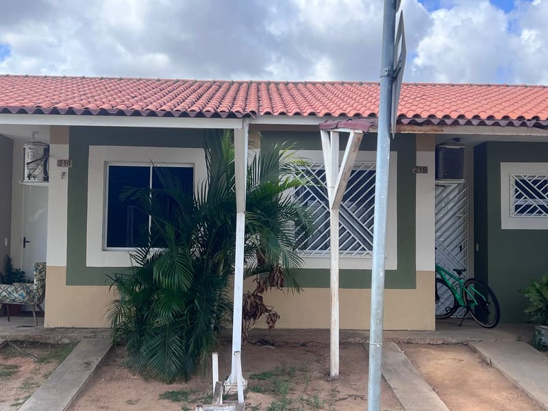 Fachada de casa térrea pintada em verde e bege, com palmeira na frente